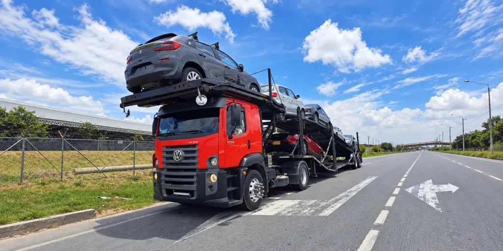 Camión niñera rojo cargado con vehículos en una carretera de Colombia.